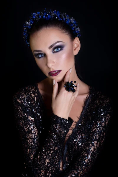 Costosos pendientes de corona de joyería y anillo en una hermosa chica morena elegante sexy con un maquillaje de noche brillante en un vestido de noche negro con encaje — Foto de Stock