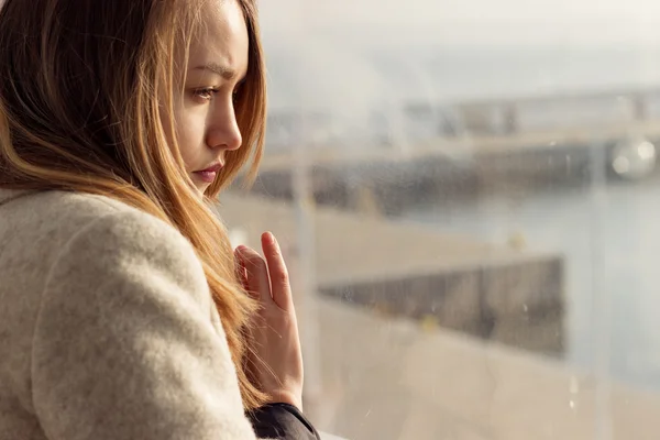 Hermosa chica triste y solitaria sentada cerca de la ventana falta — Foto de Stock