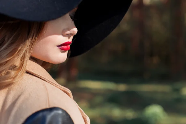 Beautiful sexy woman in elegant black hat with large fields and bright red lipstick on her lips — Stock Photo, Image