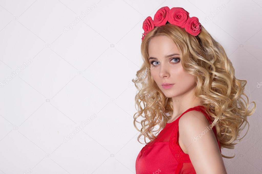 Fashionable portrait shot of a beautiful sexy girl in a cute blonde with curly hair wearing a wreath of flowers handmade in the evening image on a white background in studio