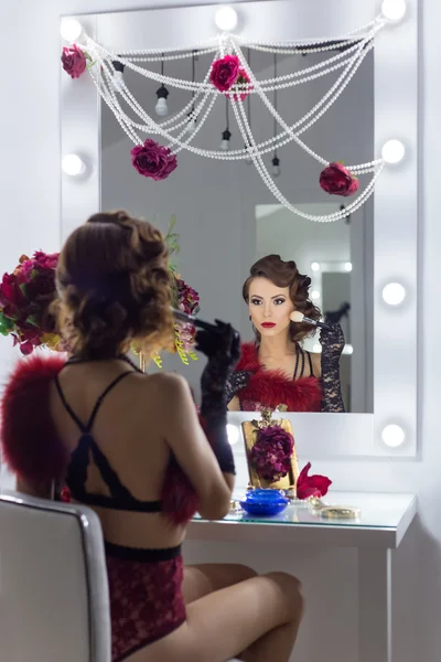 Elegant beautiful sexy girl in lace lingerie in a retro style with beautiful hair and makeup in the style of 20-ies sitting in the dressing room near the mirror — ストック写真