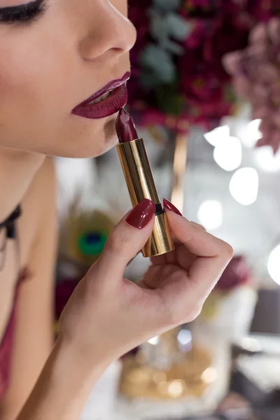 beautiful elegant sexy girl with bright makeup lipstick lipstick color Marsala in front of the mirror in the dressing room