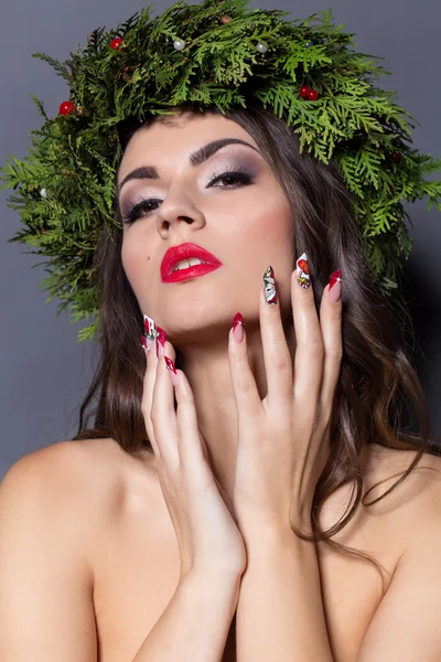 Noël élégante femme de mode. Coiffure et maquillage du Nouvel An de Noël. Magnifique style Vogue Dame avec des décorations de Noël sur la tête, boules, maquillage professionnel, rouge à lèvres rouge longue robe de soirée rouge — Photo