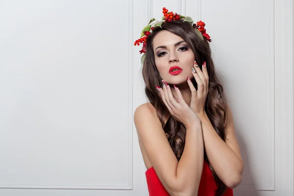 Christmas elegant fashion woman. Xmas New Year hairstyle and makeup. Gorgeous Vogue style Lady with Christmas decorations on her head, baubles, professional makeup, red lipstick long red evening dress — Stok fotoğraf
