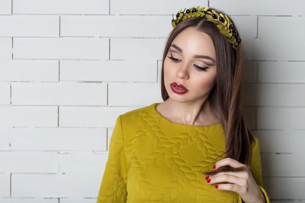 Elegante hermosa mujer sexy en vestido de noche con un maquillaje de noche brillante con labios llenos con lápiz labial rojo en los labios, y con una corona de ramas de olivo en la cabeza — Foto de Stock