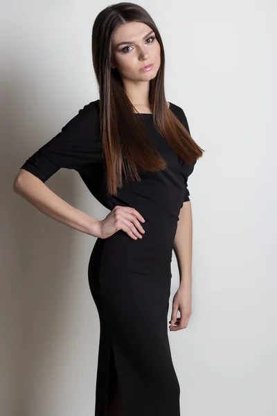 Σέξι όμορφη κομψή γυναίκα με μακριά μαλλιά, φωτεινό βραδυνό μακιγιάζ σε ένα μαύρο φόρεμα βράδυ στο studio σε λευκό φόντο — Φωτογραφία Αρχείου