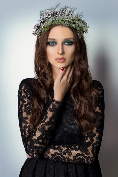 Hermosa mujer elegante delgada sexy con maquillaje brillante Smoky Eyes en la corona de Año Nuevo de árbol de Navidad y conos — Foto de Stock