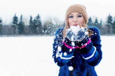 güzel sevimli seksi oynak mutlu genç kadın ile kar parkta oynarken kap mavi bir ceket