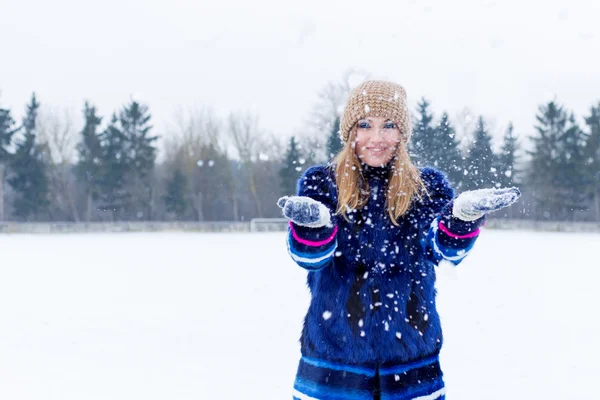 Vacker söt sexig lekfull glad ung kvinna i blå jacka i den gemensamma jordbrukspolitiken spelar med snö i parken — Stockfoto