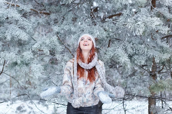 Vrij gelukkig vrolijke mooi jong meisje met haar rydimi plezier in de besneeuwde bossen en geniet van de eerste sneeuw in muts met sjaal — Stockfoto