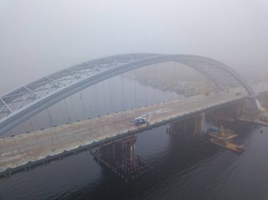 Hava aracı görüntüsü. Yoğun siste nehir boyunca kablo destekli bir köprü inşaatı.