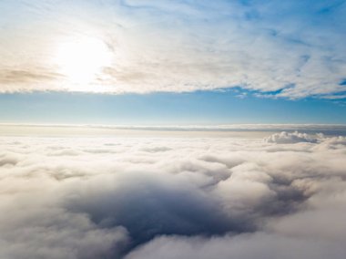 Hava görüntüsü. Güneşli bir havada, beyaz bulutların üzerinde uçuyor..