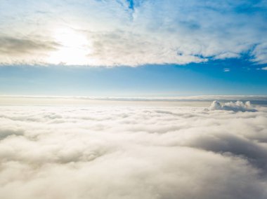 Hava görüntüsü. Güneşli bir havada, beyaz bulutların üzerinde uçuyor..