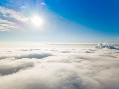 Hava görüntüsü. Güneşli bir havada, beyaz bulutların üzerinde uçuyor..