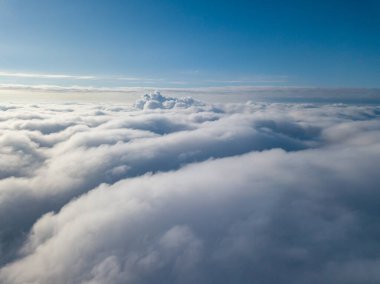 Hava görüntüsü. Güneşli bir havada, beyaz bulutların üzerinde uçuyor..