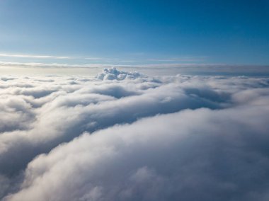 Hava görüntüsü. Güneşli bir havada, beyaz bulutların üzerinde uçuyor..