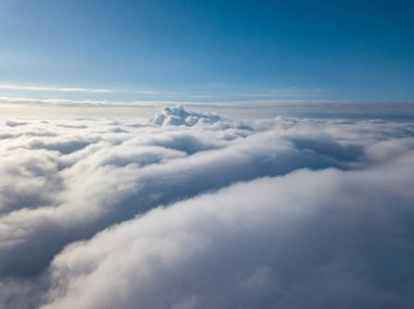 Hava görüntüsü. Güneşli bir havada, beyaz bulutların üzerinde uçuyor..