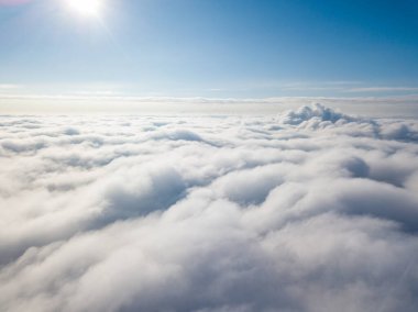 Hava görüntüsü. Güneşli bir havada, beyaz bulutların üzerinde uçuyor..