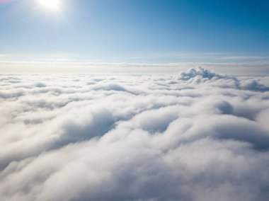 Hava görüntüsü. Güneşli bir havada, beyaz bulutların üzerinde uçuyor..
