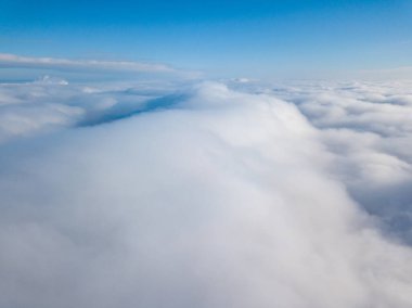 Hava görüntüsü. Güneşli bir havada, beyaz bulutların üzerinde uçuyor..