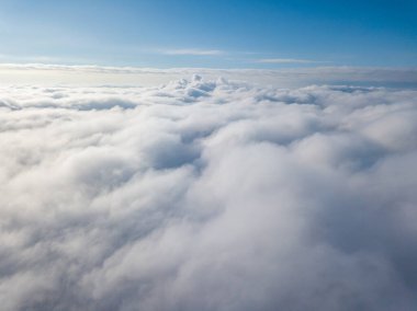 Hava görüntüsü. Güneşli bir havada, beyaz bulutların üzerinde uçuyor..