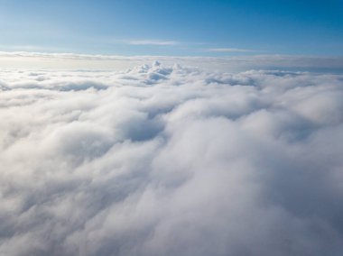 Hava görüntüsü. Güneşli bir havada, beyaz bulutların üzerinde uçuyor..