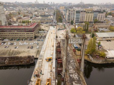Hava aracı görüntüsü. Kiev 'de Dinyeper nehri üzerinde bir köprü inşa ediliyor. Bulutlu bir sonbahar sabahı.