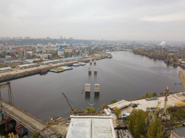 Hava aracı görüntüsü. Kiev 'de Dinyeper nehri üzerinde bir köprü inşa ediliyor. Bulutlu bir sonbahar sabahı.
