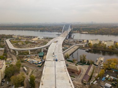 Hava aracı görüntüsü. Kiev 'de Dinyeper nehri üzerinde bir köprü inşa ediliyor. Bulutlu bir sonbahar sabahı.
