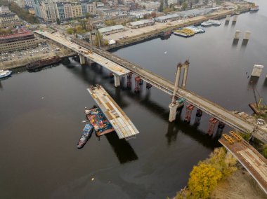 Hava aracı görüntüsü. Kiev 'de Dinyeper nehri üzerinde bir köprü inşa ediliyor. Bulutlu bir sonbahar sabahı.
