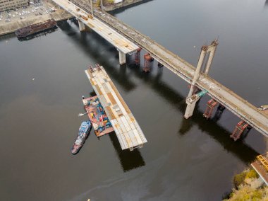 Hava aracı görüntüsü. Kiev 'de Dinyeper nehri üzerinde bir köprü inşa ediliyor. Bulutlu bir sonbahar sabahı.