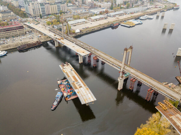 Aerial drone view. Construction of a bridge across the Dnieper river in Kiev. Cloudy autumn morning.