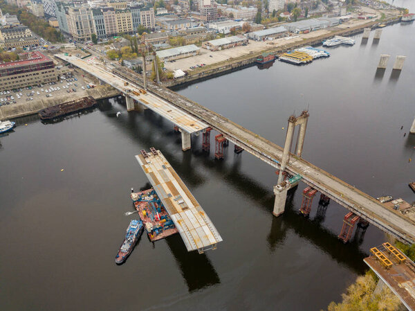 Aerial drone view. Construction of a bridge across the Dnieper river in Kiev. Cloudy autumn morning.