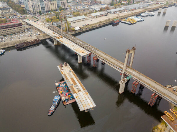 Aerial drone view. Construction of a bridge across the Dnieper river in Kiev. Cloudy autumn morning.