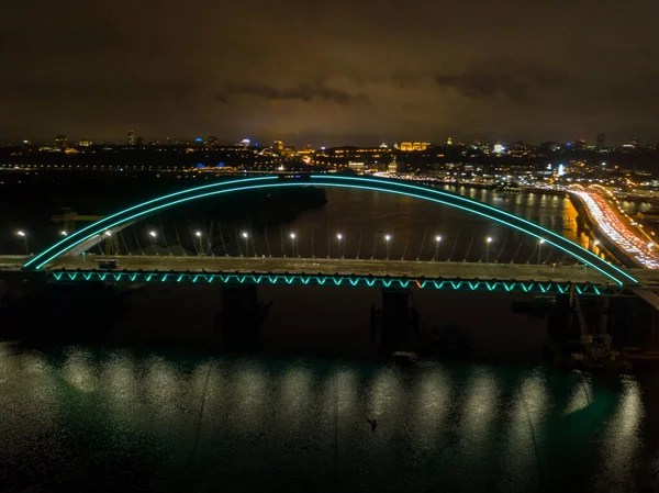 空中无人驾驶飞机视图 现代拱形斜拉桥在基辅的夜晚 桥拱的彩色照明 — 图库照片