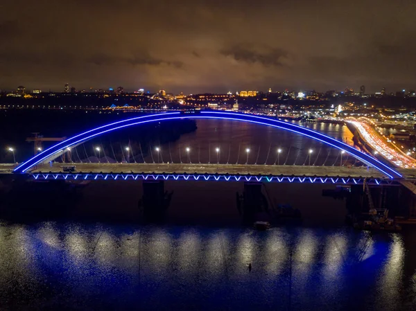 空中无人驾驶飞机视图 现代拱形斜拉桥在基辅的夜晚 桥拱的彩色照明 — 图库照片