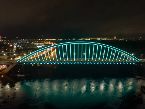 空中无人驾驶飞机视图 现代拱形斜拉桥在基辅的夜晚 桥拱的彩色照明 — 图库照片
