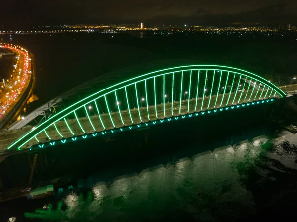 空中无人驾驶飞机视图 现代拱形斜拉桥在基辅的夜晚 桥拱的彩色照明 — 图库照片
