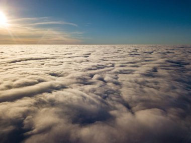 Kıvırcık bulutların üzerinde uçan hava. Güneşin ışınları bulutların üzerinde parlıyor.