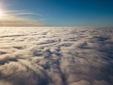 Kıvırcık bulutların üzerinde uçan hava. Güneşin ışınları bulutların üzerinde parlıyor.