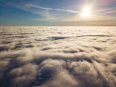 Kıvırcık bulutların üzerinde uçan hava. Güneşin ışınları bulutların üzerinde parlıyor.