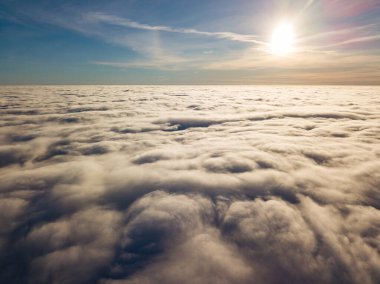 Kıvırcık bulutların üzerinde uçan hava. Güneşin ışınları bulutların üzerinde parlıyor.