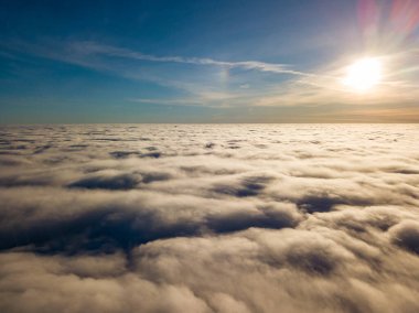 Kıvırcık bulutların üzerinde uçan hava. Güneşin ışınları bulutların üzerinde parlıyor.