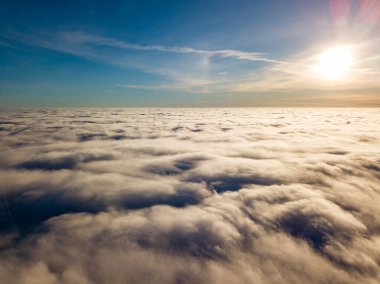 Kıvırcık bulutların üzerinde uçan hava. Güneşin ışınları bulutların üzerinde parlıyor.