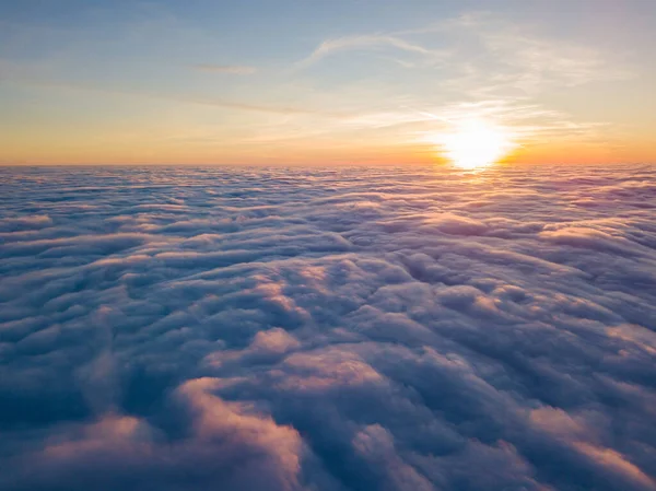 Sunset over curly clouds, aerial high flight. The last rays of the sun shine on the clouds.