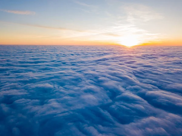 Sunset over curly clouds, aerial high flight. The last rays of the sun shine on the clouds.