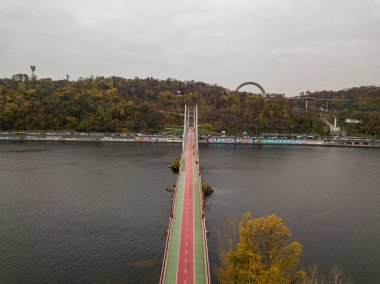 Hava aracı görüntüsü. Kiev 'deki Dinyeper Nehri üzerinde bir yaya ve bisiklet köprüsü. Köprüde kırmızı bisiklet yolu.