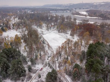 Hava aracı görüntüsü. Parkta karla kaplı ağaçlar. Dünyadaki ilk karın ince tabakası..