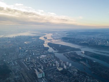 Kiev üzerinde havadan yüksek uçuş, şehrin üzerinde sis bulutu. Sonbahar sabahı, Dinyeper Nehri ufukta görünüyor..