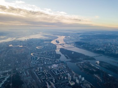 Kiev üzerinde havadan yüksek uçuş, şehrin üzerinde sis bulutu. Sonbahar sabahı, Dinyeper Nehri ufukta görünüyor..